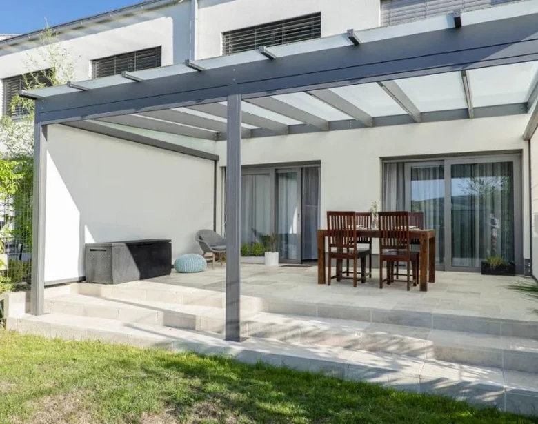 Moderní kovová pergola s jídelním setem na terase domu.