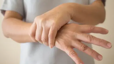 Osoba drží vlastní zápěstí v gestu naznačujícím třes nebo bolest.