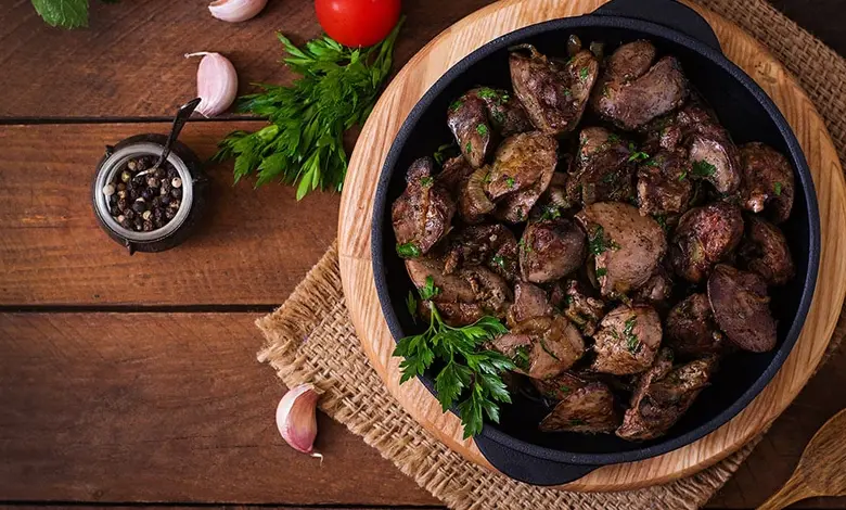 Připravená vepřová játra s čerstvou petrželkou na dřevěném podkladu