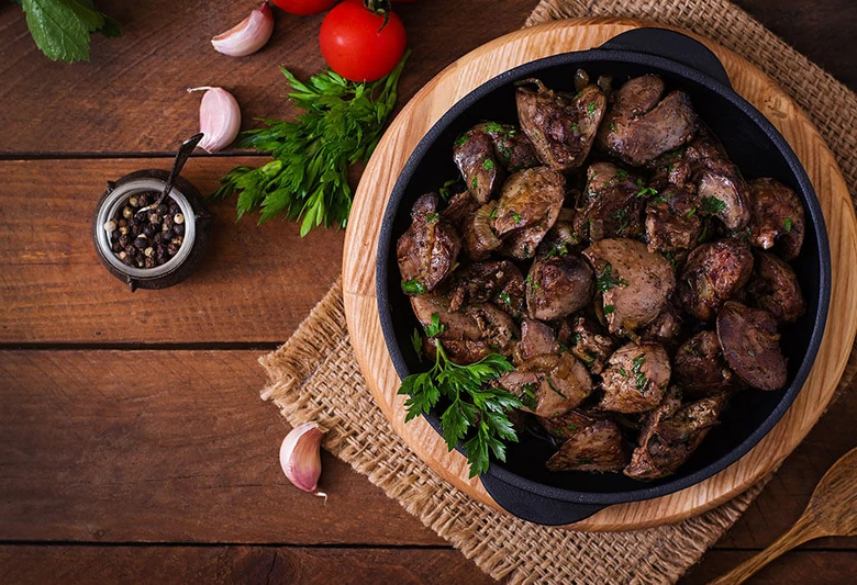Připravená vepřová játra s čerstvou petrželkou na dřevěném podkladu