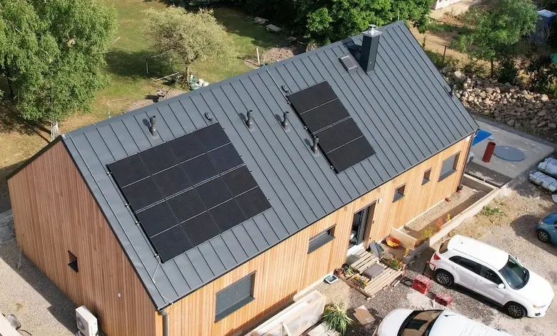 Dům s fotovoltaickými panely na střeše v přírodě.