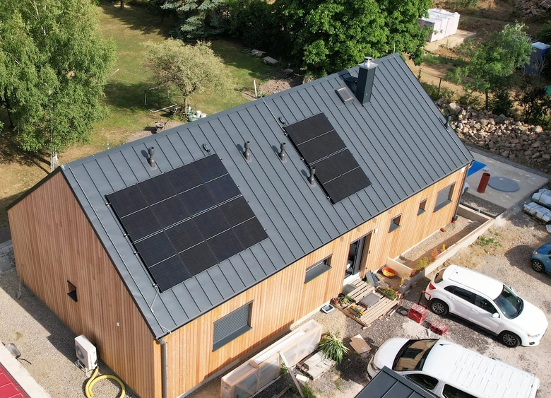 Dům s fotovoltaickými panely na střeše v přírodě.