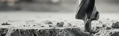 Vrták v betonu při práci s předměty pro stavbu.