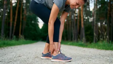 Žena se natahuje v lese pro péči o achillovu šlachu.