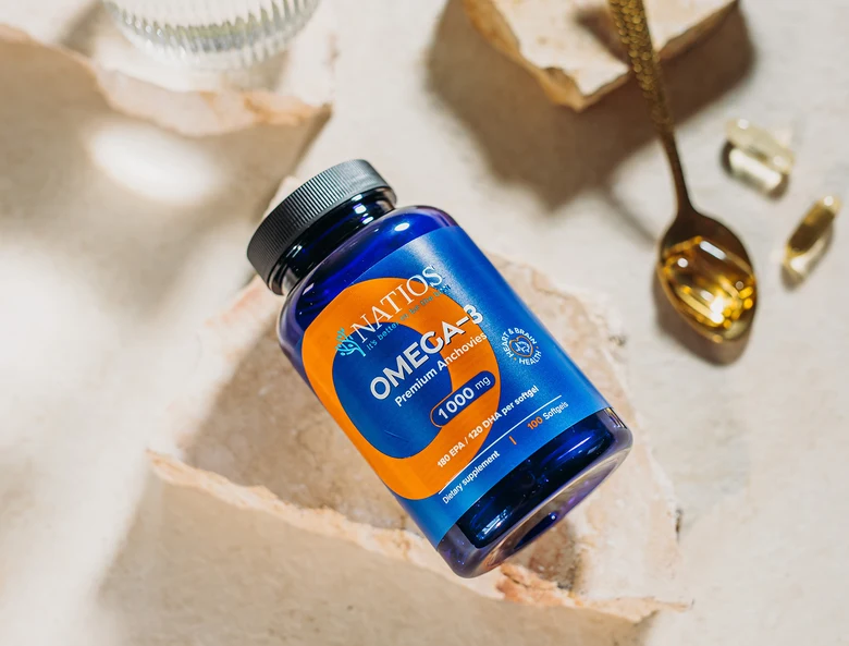 Modrá lahvička s doplňkem stravy omega-3 vedle kapsule.