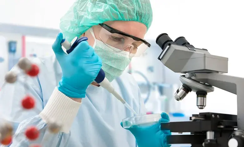 Vědec pipetou přenáší tekutinu do Petrijeho misky v laboratoři.