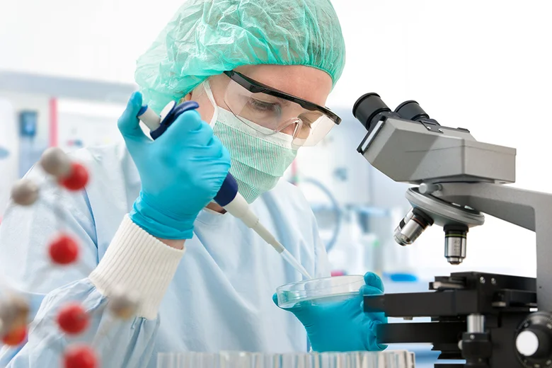 Vědec pipetou přenáší tekutinu do Petrijeho misky v laboratoři.