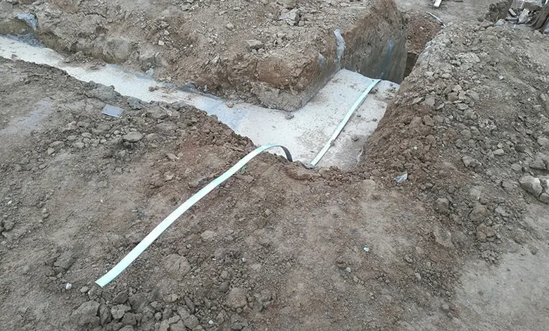Bílý uzemňovací vodič položený v jámě u základové desky.
