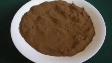 Bílý talíř s hnědým práškem na tmavém pozadí.