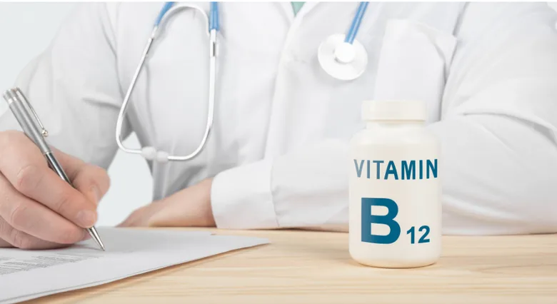 Lékař píše předpis vedle lahvičky vitaminu B12.