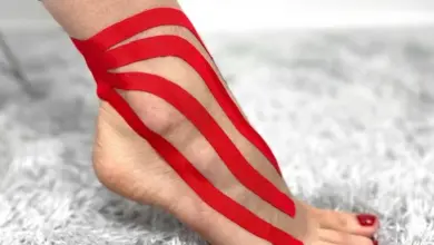 Červená kinéziotape na kotníku při léčbě podvrtnutí