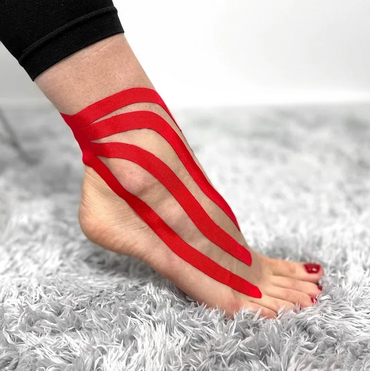 Červená kinéziotape na kotníku při léčbě podvrtnutí