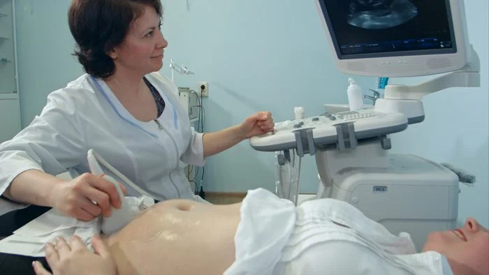 Lékařka provádí ultrazvukové vyšetření břicha těhotné ženy.