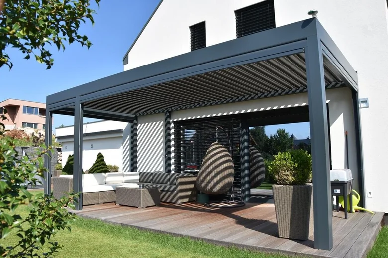 Moderní šedá pergola s venkovním posezením na dřevěné terase.