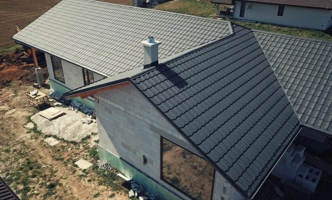 Stavba domu s novou střechou z plechových tašek.