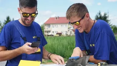 Dva stavebníci kontrolují dokumenty na venkovním stole.